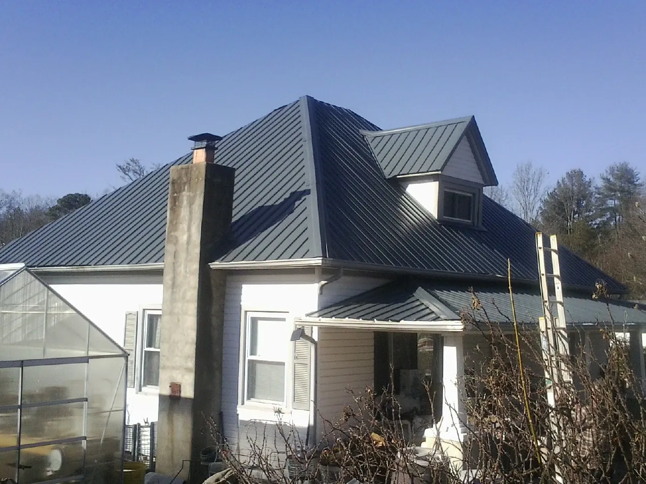 Dark blue standing seam metal roof on a white farmhouse with dormer — Slate & Tile Roof Repair by Roofing Brothers in East Ellijay