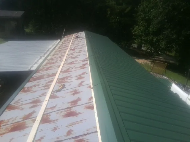Old rusted panels beside newly installed green metal roofing — Wind Damage Roof Repair by Roofing Brothers in East Ellijay