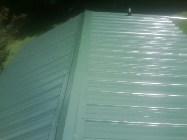 New green metal panels meeting at the ridge of a roof — Flat Roof Repair work by our crew in East Ellijay