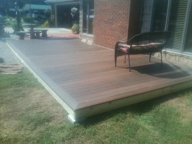 New wood deck and wicker chair beside a brick house in East Ellijay