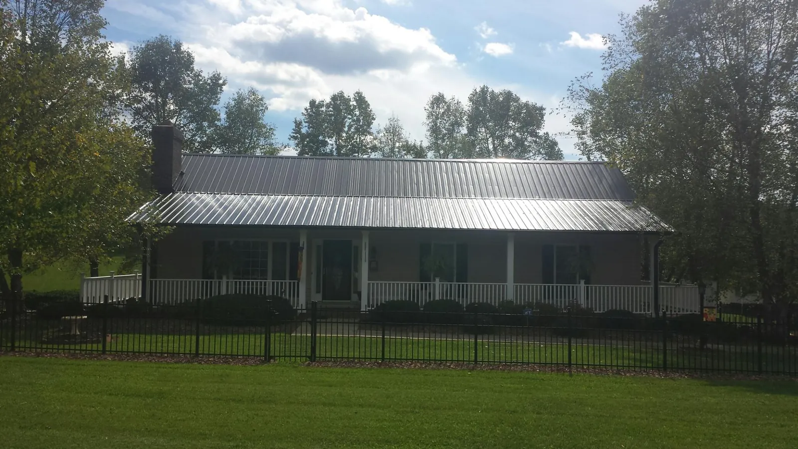 Gray metal roof on a brick ranch with a full width front porch — Gutter Guard Installation work by our crew in East Ellijay