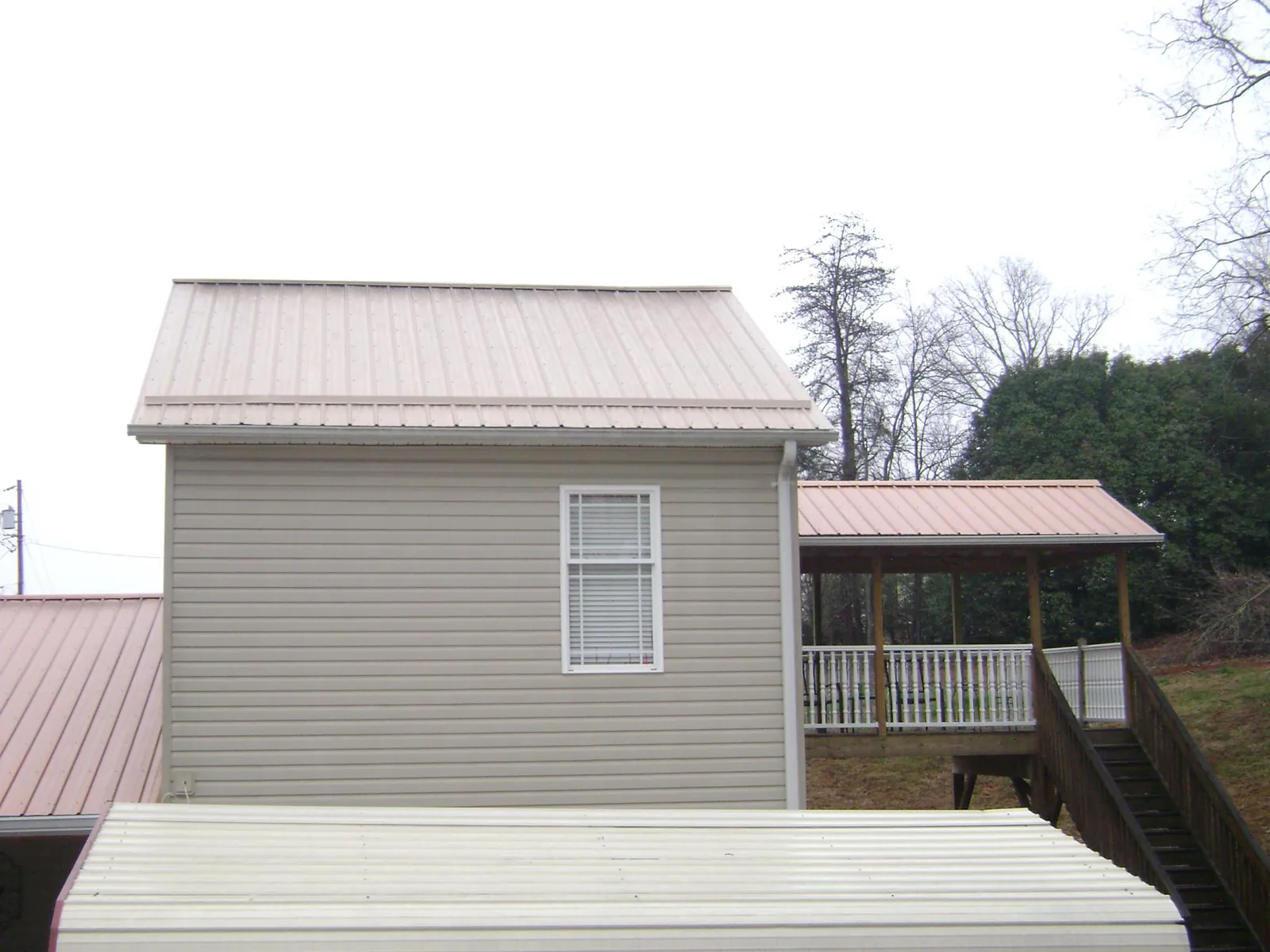 Tan metal roofs on a two story addition and attached porch, from a Roof Replacement job in East Ellijay
