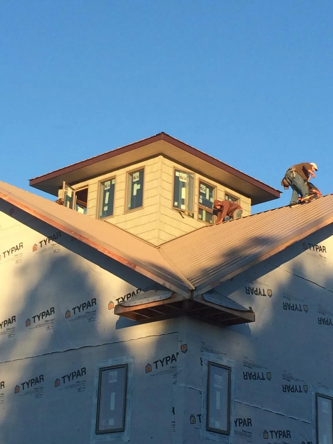 Roofers working around a rooftop cupola on a new metal roof at sunset — Roof Waterproofing in East Ellijay by Roofing Brothers